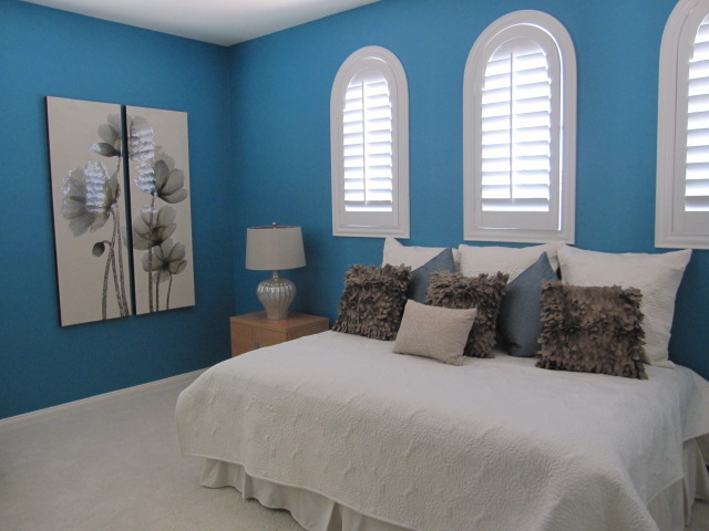 Bedroom with arched white shutters.